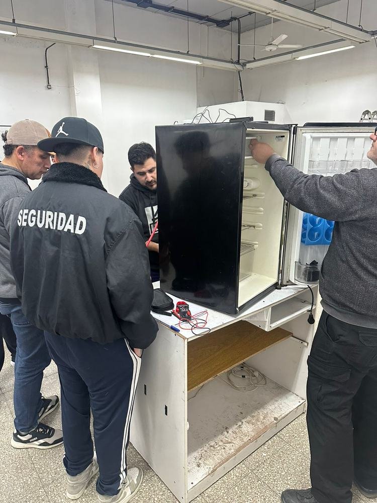 Grupo reparando una heladera comercial